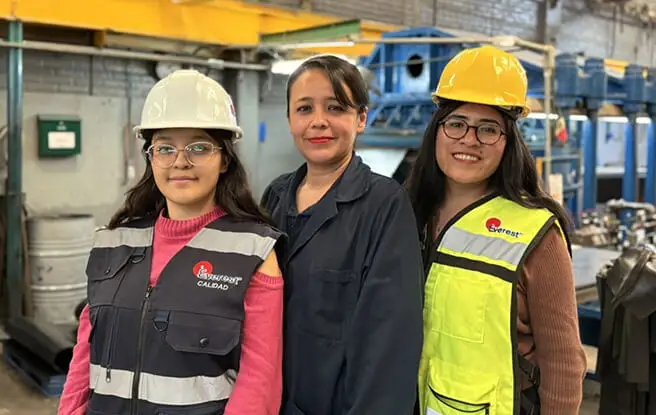 Equipo de calidad de Grupo Everest con chalecos y cascos de seguridad posando en planta de producción