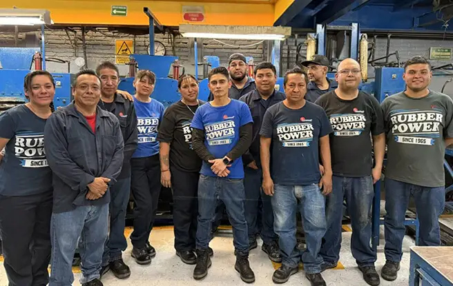 Equipo completo de trabajadores de Grupo Everest posando con uniforme corporativo frente a la planta